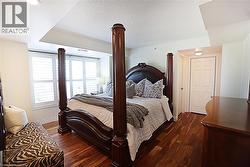 Bedroom featuring wood-finish flooring, recessed lighting, and white plantation shutters - 