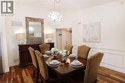Dining area featuring wood-finish flooring, a crystal chandelier, and wainscoting - 