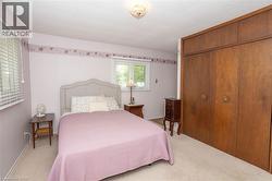 Carpeted room with a full-wall built-in closet featuring wood-finish doors and decorative hardware - 