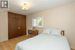 Light wood-finish flooring with a flush-mount ceiling light fixture, a window with horizontal blinds, and a built-in closet with wood doors - 