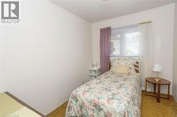 Bedroom featuring a single window with blinds, light-toned walls, and soft carpet flooring - 