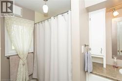 Bathroom featuring a window, a shower with a curtain rod, a built-in cabinet, a vanity with a countertop, and a wall-mounted light fixture - 