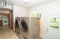 Laundry area featuring a side-by-side washer and dryer set on pedestals, tiled flooring, and an exterior door with a window - 