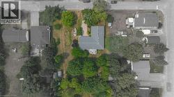 Property featuring a dark roof, established trees, and a visible garden area - 