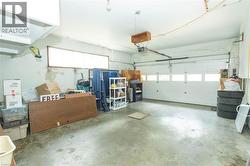 Spacious garage featuring a large automatic overhead door with upper window panels, a concrete floor, and a long horizontal window providing natural illumination - 
