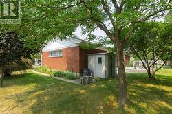 Expansive green lawn featuring mature trees and a brick-sided exterior with white trim - 