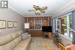 Living area featuring a built-in wall unit, ceiling fan, and crown molding - 