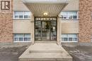 Building facade featuring a prominent main entrance, light brick exterior, and decorative stone accents - 237 Mohawk Road E Unit# 16, Hamilton, ON  - Outdoor 