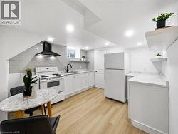 Modern kitchen with light wood-finish flooring, white cabinetry, and white countertops - 