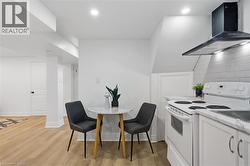Kitchen featuring white cabinetry, light-toned countertops, a white electric range, and a black range hood - 