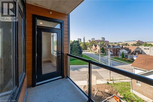 Private balcony featuring concrete flooring, a glass railing with a black metal frame, and wood-finish siding - 72 Erb Street E Unit# 102, Waterloo, ON - Outdoor With Balcony With Exterior