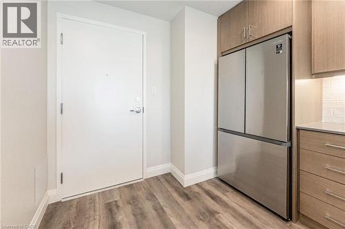 Modern stainless steel refrigerator integrated into wood-finish cabinetry - 72 Erb Street E Unit# 102, Waterloo, ON - Indoor