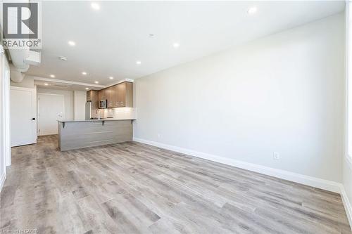 Open-concept living space featuring wood-finish flooring, recessed lighting, and a modern kitchen island with an integrated sink - 72 Erb Street E Unit# 102, Waterloo, ON - Indoor Photo Showing Kitchen