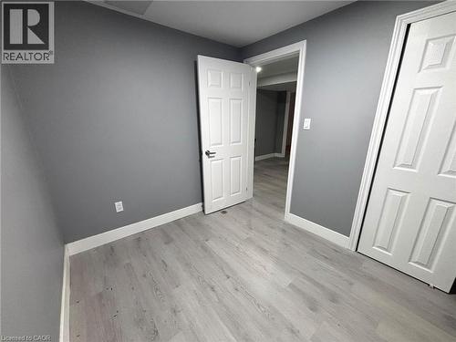 Room featuring light wood-finish flooring, grey painted walls, white trim, and white paneled doors - 490 Third Street Unit# 40, London, ON - Indoor Photo Showing Other Room