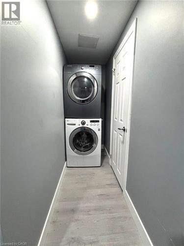 Dedicated laundry area featuring a stacked washer and dryer, wood-finish flooring, recessed lighting, and a paneled interior door - 490 Third Street Unit# 40, London, ON - Indoor Photo Showing Laundry Room