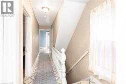 Hallway with a painted white balustrade and handrail, neutral tone wall paint, and patterned flooring - 
