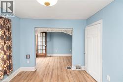 Room featuring light blue walls, wood-finish flooring, and white trim - 