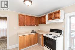 Kitchen featuring a compact layout with upper and lower cabinetry, laminate countertops, a stainless steel sink, and a white electric range with an overhead exhaust fan - 