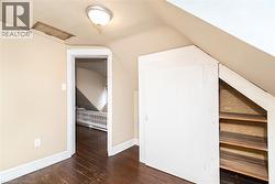 Attic room featuring sloped ceilings, dark wood-finish flooring, and built-in storage with shelving - 