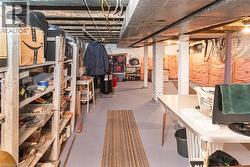 Basement space featuring painted concrete flooring, exposed ceiling joists, and brick support columns - 