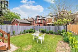 Expansive backyard with a manicured lawn, a wooden privacy fence, and mature trees - 