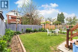 Expansive backyard featuring a lush lawn, perimeter garden beds, a privacy fence, and a wood-finish deck with stairs - 