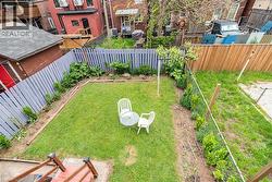 Gated backyard featuring a manicured lawn, perimeter planting beds, and a combination of wood and picket fencing - 