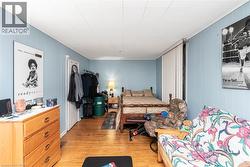 Room with wood-finish flooring, light blue vertical paneling, and a white paneled ceiling - 