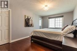 Room featuring rich wood-finish flooring, light grey painted walls, and a white six-panel door - 