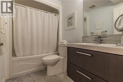 Bathroom featuring a white bathtub with shower, wood-finish vanity with two drawers, and a white integrated sink - 44 Lemon Grass Street, Kitchener, ON - Indoor Photo Showing Bathroom