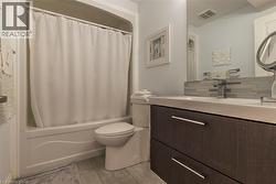 Bathroom featuring a white bathtub with shower, wood-finish vanity with two drawers, and a white integrated sink - 