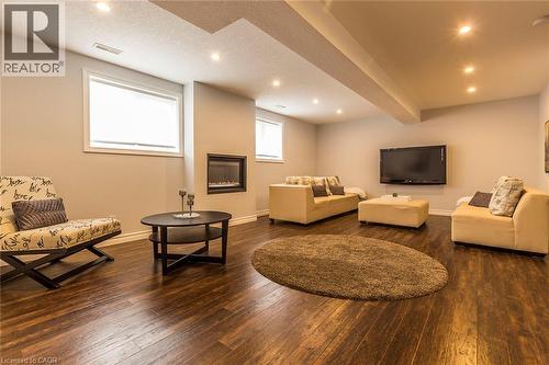 Spacious finished room featuring rich wood-finish flooring, recessed lighting, and an inset fireplace - 44 Lemon Grass Street, Kitchener, ON - Indoor