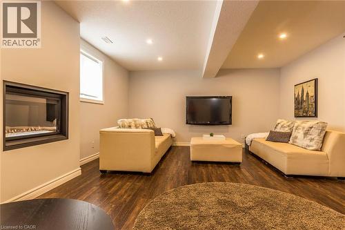 Recessed fireplace with a dark surround, wood-finish flooring, and recessed ceiling lighting - 44 Lemon Grass Street, Kitchener, ON - Indoor