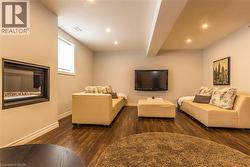 Recessed fireplace with a dark surround, wood-finish flooring, and recessed ceiling lighting - 