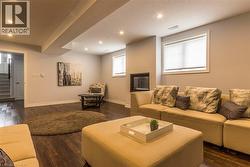 Recreation room featuring recessed lighting, wood-finish flooring, a built-in electric fireplace, and two windows with blinds - 