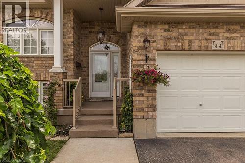 Brick facade residence featuring an arched entry with a decorative glass front door, concrete steps, and a white paneled garage door - 44 Lemon Grass Street, Kitchener, ON - Outdoor With Exterior