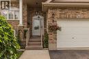 Brick facade residence featuring an arched entry with a decorative glass front door, concrete steps, and a white paneled garage door - 44 Lemon Grass Street, Kitchener, ON  - Outdoor With Exterior 