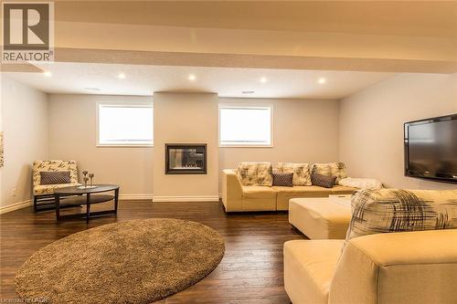 Spacious living area featuring rich wood-finish flooring, recessed lighting, and a modern wall-mounted fireplace - 44 Lemon Grass Street, Kitchener, ON - Indoor With Fireplace
