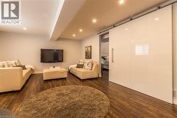 Spacious entertainment area featuring wood-finish flooring and recessed lighting - 