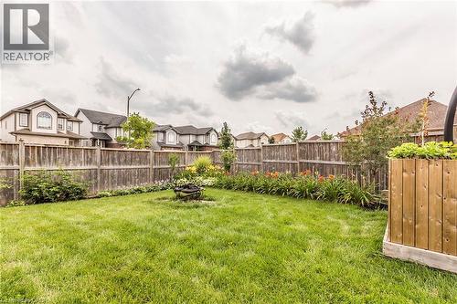 Expansive backyard featuring a lush lawn, perimeter wood fencing, and established garden beds with floral plantings - 44 Lemon Grass Street, Kitchener, ON - Outdoor