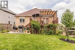 Expansive rear yard featuring a wooden deck with railing, a pergola with a retractable canopy, and a concrete patio - 