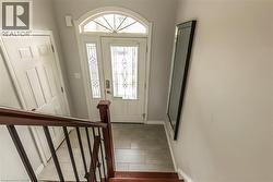 Entryway featuring a white door with decorative glass inserts, an arched transom window, and a tiled floor - 