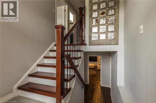 Staircase featuring dark wood-finish treads, white risers, and a dark wood newel post with black metal balusters - 44 Lemon Grass Street, Kitchener, ON - Indoor Photo Showing Other Room