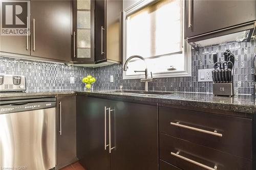 Kitchen featuring dark wood cabinetry with brushed nickel hardware, a dark speckled countertop, and a mosaic tile backsplash - 44 Lemon Grass Street, Kitchener, ON - Indoor Photo Showing Kitchen