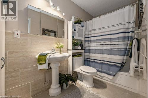 Bathroom featuring a pedestal sink, a three-door mirrored medicine cabinet, and a tiled shower/tub combination - 75 Hazelglen Drive Unit# 308, Kitchener, ON - Indoor Photo Showing Bathroom