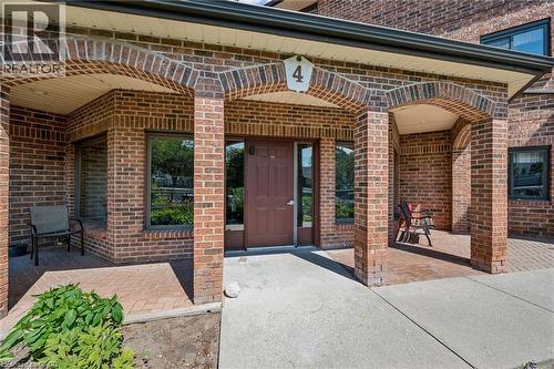 Brick exterior featuring arched entryways, a solid panel door, and multiple windows with dark frames - 4 Albert Street Unit# 105, Cambridge, ON - Outdoor With Exterior