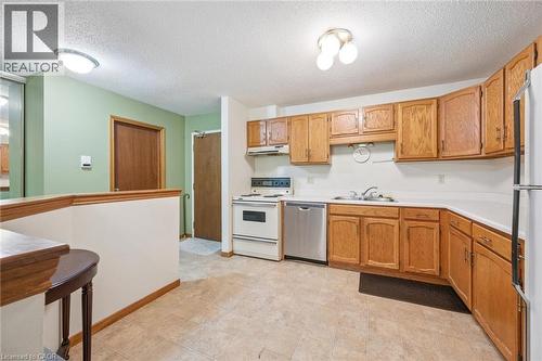 Kitchen featuring wood cabinetry, laminate countertops, and tile flooring - 4 Albert Street Unit# 105, Cambridge, ON - Indoor Photo Showing Kitchen With Double Sink