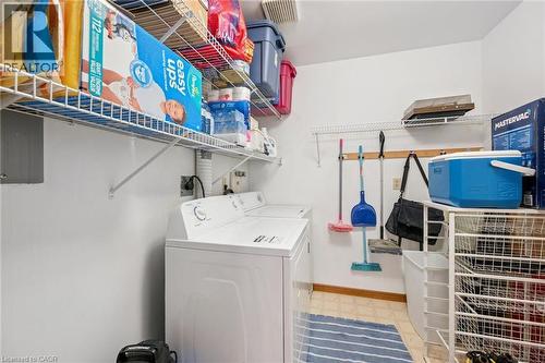 Dedicated utility space featuring washer and dryer hookups, overhead wire shelving, and a wall-mounted storage rack - 4 Albert Street Unit# 105, Cambridge, ON - Indoor Photo Showing Laundry Room