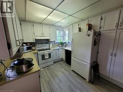 Kitchen featuring white cabinetry, light wood-finish countertops, stainless steel sink, and wood-finish flooring - 