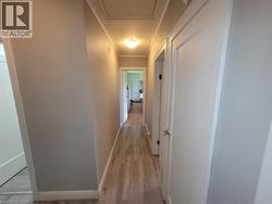 Hallway with wood-finish flooring, light gray wall paint, white trim, and a flush-mount ceiling light fixture - 